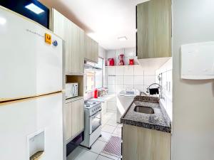 a white kitchen with a sink and a refrigerator at Apê Completo com Piscina I Wi-Fi e A/C in Imperatriz +26 photos