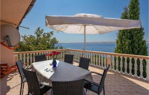 a table with a white umbrella on a balcony at Cozy Apartment In Baric Draga in Barić Draga