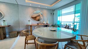 a dining room with a glass table and a mirror at COBERTURA com belíssima vista para o mar e jacuzzi in Itapema