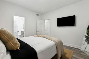 a white bedroom with a bed and a tv on the wall at 15 Bedrooms in the Heart of NOLA in New Orleans