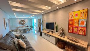 a living room with a couch and a flat screen tv at COBERTURA com belíssima vista para o mar e jacuzzi in Itapema