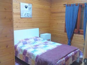 a bedroom with a bed in a room with wooden walls at Casa dos Manos in Furnas