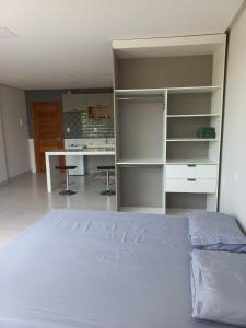 a bedroom with a bed and a desk and shelves at Pousada Studio Flat Jequié in Jequié
