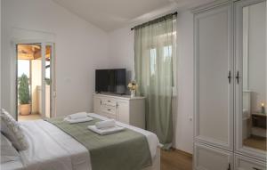 a white bedroom with a bed and a television at 4 Bedroom Lovely Home In Pusti in Peresiji +33 photos