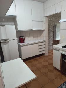 a white kitchen with white cabinets and a refrigerator at Expo São Paulo, casa aconchegante in Sao Paulo
