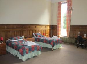 a room with two beds and a desk and a window at University Hall - Campus Accommodation in St Andrews