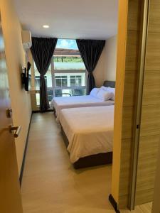 una camera da letto con due letti e una finestra di T Lodge, Kapit a Kapit