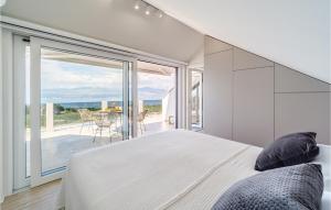 a bedroom with a large white bed and a balcony at Beautiful Home In Splitska- Supetar in Donji Humac