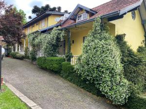 a yellow house with bushes next to a street at Apartamentos Sulla Collina Centro de Gramado localizado próximo da rua Coberta in Gramado