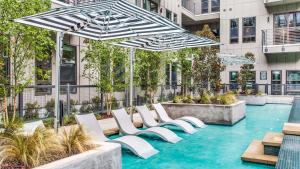einen Außenpool mit weißen Stühlen und Sonnenschirmen in der Unterkunft Cityscape Luxury Living Downtown Fort Worth Condo, Pool, Gym, Parking, BBQ in Fort Worth