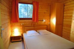 a bedroom with a bed in a wooden cabin at Gite De Boshut in Oignies-en-Thierache