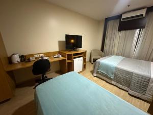 a hotel room with two beds and a desk with a television at Flat 213 - Comfort Hotel Taguatinga in Taguatinga +3 photos