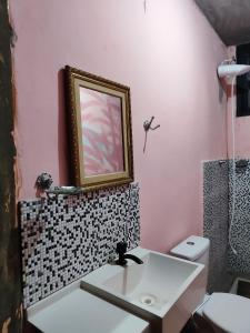 baño con lavabo y una foto en la pared en Recanto Pousada Elshaday sede, en Osvaldo Cruz