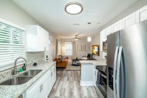 Una cocina con gabinetes blancos y un refrigerador de acero inoxidable. en Saint Pete Hideaway Cozy Urban Escape Oasis, en San Petersburgo