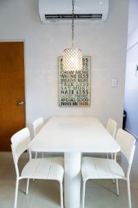 a white dining room table with white chairs and a chandelier at 103-Delightful GEM in the city, Close to the Beach with Free Parking in San Juan +2 photos