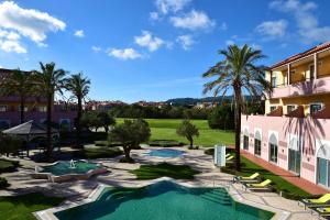 a resort with a swimming pool and palm trees at Pestana Sintra Golf Resort & SPA Hotel in Sintra
