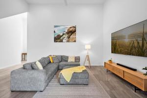 a living room with a couch and a tv at Beautiful Three-Story Villa footsteps to the Beach in Coolum Beach