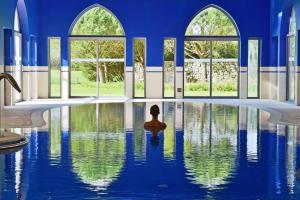 una persona sentada en una piscina en una habitación con ventanas en Pestana Sintra Golf Resort & SPA Hotel en Sintra