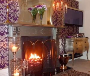 a fireplace in a living room with candles and flowers at Shelbourne House in Harrogate