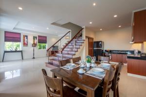a dining room with a table and chairs and a staircase at Prima Villas Karon Phuket in Karon Beach