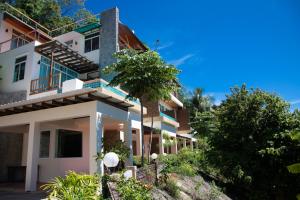 a white building with a tree in front of it at Prima Villas Karon Phuket in Karon Beach