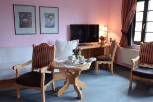 ein Wohnzimmer mit einem Tisch, Stühlen und einem Schreibtisch in der Unterkunft Hotel Landhaus Marienstein in Bergen