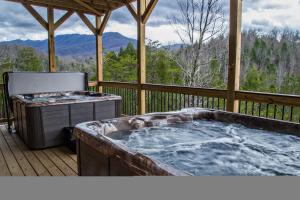a hot tub on a deck with a grill at Greenbrier Estate Cabin in Pittman Center