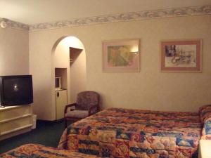 a hotel room with a bed and a chair and a television at O'Hare Inn & Suites in Schiller Park