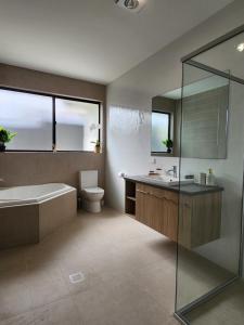 a bathroom with a tub and a toilet and a sink at Holiday at the Beach, Spa Bath, King Bed with TV in Christies Beach +19 photos