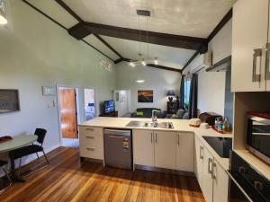a kitchen with white cabinets and a table in it at The Church House- Boutique Comfort in Balclutha
