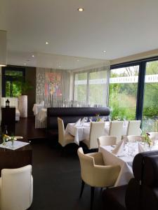 un restaurante con mesas y sillas blancas y ventanas en Guesthouse Lichtenau, en Nußloch