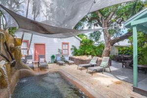 a backyard with a pool with chairs and a tree at Pilar Cottage - Harbor Walk Hideaways in Key West