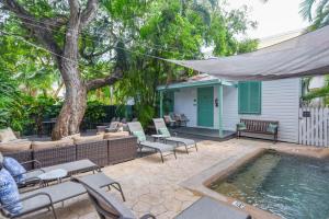 een achtertuin met een zwembad, stoelen en een huis bij African Queen - Harbor Walk Hideaways in Key West