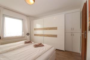 Dos camas en una habitación blanca con ventana. en Bungalow-Marina, en Norddeich