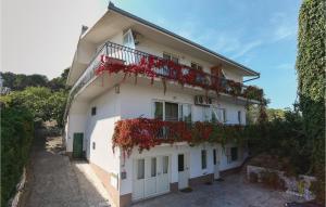 ein weißes Gebäude mit roten Blumen auf dem Balkon in der Unterkunft Apartment Put Vlaka Iii in Trogir