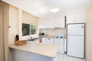 a kitchen with white cabinets and a white refrigerator at Beachpoint, 401 in Forster