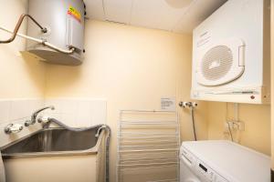 a small kitchen with a sink and a washing machine at Beachpoint, 401 in Forster +5 photos