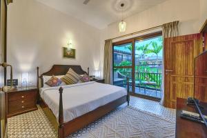a bedroom with a bed and a sliding glass door at Melhor Stays Villa - L-A3 Luxurious 3BHK villa with private pool, Assagao in Vagator
