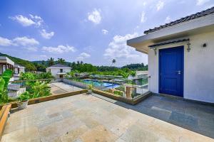 an outdoor patio with a blue door and a pool at Melhor Stays Villa - L-M102 Luxurious 4BHK villa with private pool, Anjuna in Anjuna