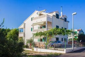 a white building with a car parked in front of it at Apartments Srdarev Pencov in Vodice