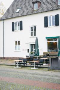 a white building with tables and umbrellas in front of it at Stilvolles Apartment in stadtnähe-Parkplatz- 4 Personen- Balkon in Wolfsburg