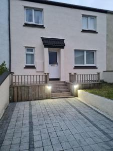 a white house with a wooden fence and stairs at Modern 3 Bedroom Property centrally based in Balivanich