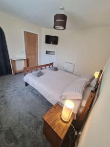 a bedroom with a bed and a table with a lamp at Modern 3 Bedroom Property centrally based in Balivanich