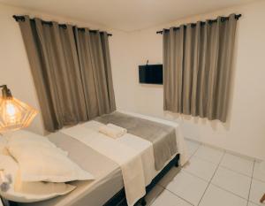 ein Schlafzimmer mit einem Bett und einem Fenster mit Vorhängen in der Unterkunft Grande Apartamento Com 3 Quartos e Uma Localização Privilegiada in Campina Grande