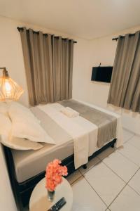 Schlafzimmer mit einem Bett und einem Tisch mit Fernbedienung in der Unterkunft Grande Apartamento Com 3 Quartos e Uma Localização Privilegiada in Campina Grande