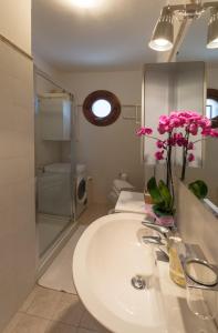 un bagno con lavandino e fiori rosa in vaso di Bellavista Apartment a Marina di Ravenna