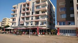 a large apartment building with tables and umbrellas on the beach at Alex's Apartment 2 in Durrës