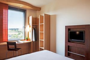 Un dormitorio con una cama, un escritorio y un televisor. en Ibis Oviedo, en Oviedo