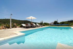a large swimming pool with chairs and an umbrella at Casa da Nora in Silves