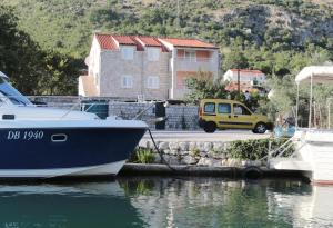 a yellow car parked next to a boat in the water at Villa Konalic in Mokošica